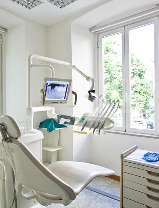 Modern dental operatory with chair, overhead light, monitor, and window at St. Helena Dental Studio.