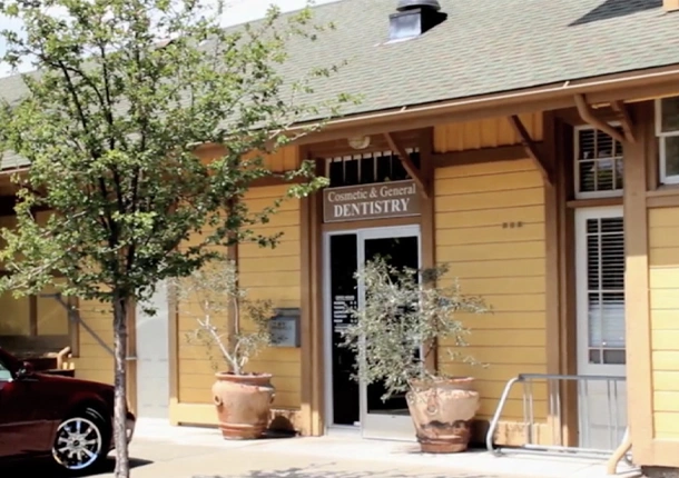 Charming wooden storefront with "Dentistry" sign, potted plants, and welcoming entrance on sunny day.